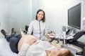 Portrait of young attractive female doctor, posing to camera with smile while conducting ultrasound scanning procedure