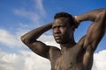 Portrait of young attractive and fit black afro American man with strong muscular body posing cool model attitude on the beach