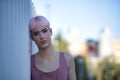 Portrait of young, attractive, gay man, heavily makeup, with pink hair and top, looking at camera sad and melancholic, head