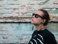 Portrait of young attractive girl in black t-shirt and sunglasses in rock style on urban background listening to music Royalty Free Stock Photo