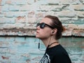 Portrait of young attractive girl in black t-shirt and sunglasses in rock style on urban background listening to music Royalty Free Stock Photo