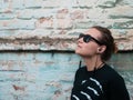 Portrait of young attractive girl in black t-shirt and sunglasses in rock style on urban background listening to music Royalty Free Stock Photo