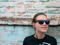 Portrait of young attractive girl in black t-shirt and sunglasses in rock style on urban background listening to music Royalty Free Stock Photo