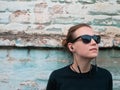 Portrait of young attractive girl in black t-shirt and sunglasses in rock style on urban background listening to music Royalty Free Stock Photo