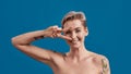 Portrait of a young attractive half naked tattooed woman with perfect skin looking happy, holding hand on eyes and Royalty Free Stock Photo