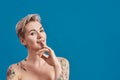 Portrait of a young attractive half naked tattooed woman with perfect skin looking playful, holding finger on her mouth Royalty Free Stock Photo