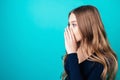 Portrait of a young attractive happy woman with blonde hair and makeup whispers a secret mystery in the studio on a blue