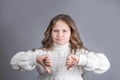 Portrait of a young attractive little girl with blond hair in sweater dissatisfied skeptic showing thumbs down dislike,disapproval Royalty Free Stock Photo