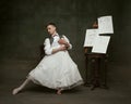 Portrait of young attractive man dressed in vintage formal suit and dancing with white woman's dress fitting in his Royalty Free Stock Photo