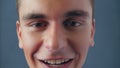 Portrait of a young attractive man malevolent talking directly to the camera on a gray background in studio. Close up