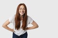 Portrait of young attractive redhead woman isolated on white background standing with her hands akimbo, who leaned in and smiling Royalty Free Stock Photo