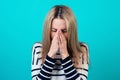 Portrait of a young attractive sick female person with blonde hair and makeup cough and sneeze in the studio on a blue