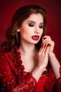 Portrait of a young, attractive vampire woman in a red rococo dress posing isolated against a dark background with red backlights Royalty Free Stock Photo