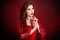Portrait of a young, attractive vampire woman in a red rococo dress posing isolated against a dark background with red backlights Royalty Free Stock Photo
