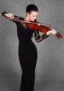 Portrait of a young attractive violinist woman in a black evening dress