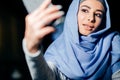 Arabian muslim woman taking selfie with phone in cafe