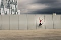 Portrait of young and attractive woman jumping next to the wall in urban park.