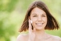 Portrait of young attractive woman putting cream on her face