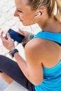 Portrait of young attractive woman sitting while using and listening to music on her smartphone in park Royalty Free Stock Photo