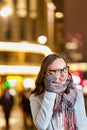 Portrait of young attractive woman smiling and talking on smartphone while holding paper bags at night shopping Royalty Free Stock Photo