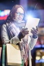 Portrait of young attractive woman smiling and using digital tablet while on night shopping Royalty Free Stock Photo