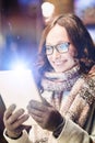 Portrait of young attractive woman smiling and using digital tablet while on night shopping Royalty Free Stock Photo