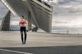 Portrait of young and attractive woman in sportswear standing in urban park.