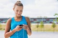 Portrait of young attractive woman standing while using and listening to music on her smartphone in park Royalty Free Stock Photo