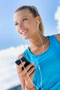 Portrait of young attractive woman standing while using and listening to music on her smartphone in park Royalty Free Stock Photo