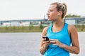 Portrait of young attractive woman standing while using and listening to music on her smartphone in park Royalty Free Stock Photo