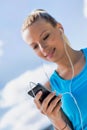 Portrait of young attractive woman standing while using and listening to music on her smartphone in park Royalty Free Stock Photo