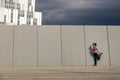 Portrait of young and attractive woman stretching next to the wall in urban park.