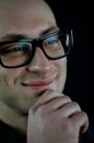 Portrait of a young bald man in black eyeglasses holding his chin with his hand while thinking looking away Royalty Free Stock Photo