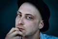Portrait of a young bald man with a black hat holding his chin with his hand and looking thoughtful as he looks in front of him Royalty Free Stock Photo