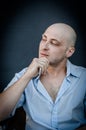 Portrait of a young bald man holding his chin with his hand and looking thoughtful as he looks away Royalty Free Stock Photo