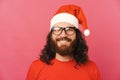 Portrait of young bearde man wearing glasses and santa claus hat over pink background Royalty Free Stock Photo