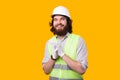 A portrait of an young bearded architect smiling is looking at the camera wearing a helmet some gloves and a Royalty Free Stock Photo