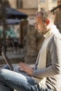 Portrait of a young bearded businessman working with laptop outdoors (Freelancer, success, knowledge, victory, money)