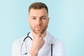 Portrait young bearded doctor with stethoscope over neck in medical coat standing against isolated blue background Royalty Free Stock Photo