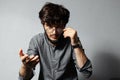 Portrait of young bearded guy with disheveled hair, touching his glasses, looking and pointing with hand at the camera. Royalty Free Stock Photo