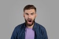 Portrait of young bearded guy shouting furiously, expressing his anger over grey studio background. Negative emotions Royalty Free Stock Photo