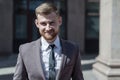 Portrait of a young bearded guy of twenty-five years old, in a business suit, against the background of an office building. Posing Royalty Free Stock Photo