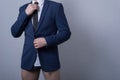 Portrait of a young bearded handsome businessman guy, in a business suit. standing without pants on a gray background, looking to Royalty Free Stock Photo