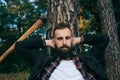 Portrait of a young bearded lumberjack resting near a tree in the woods Royalty Free Stock Photo