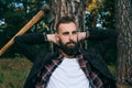 Portrait of a young bearded lumberjack resting near a tree in the woods Royalty Free Stock Photo