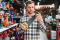 Portrait of young bearded man choosing saw on tree in hardware store Royalty Free Stock Photo