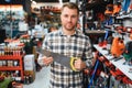 Portrait of young bearded man choosing saw on tree in hardware store Royalty Free Stock Photo