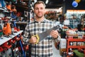 Portrait of young bearded man choosing saw on tree in hardware store Royalty Free Stock Photo