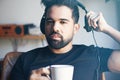 Portrait of young bearded man in headphones listening to music at home and drinking coffee. Relaxing and rest time Royalty Free Stock Photo