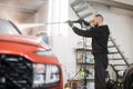 Portrait of of young bearded man worker washing red car under high pressure water Royalty Free Stock Photo